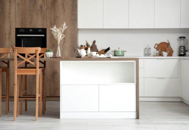 Modern mutfakta kahvaltı masası ve vazosu olan ahşap bir ada.