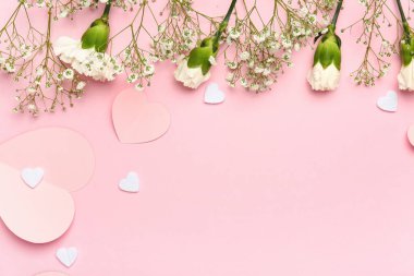 Beyaz karanfiller, çingene çiçekleri ve pembe arka planda kağıt kalpler. Sevgililer Günü konsepti
