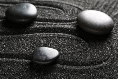 Siyah kumlar üzerinde kaplıca taşları, yakın çekim. Zen kavramı