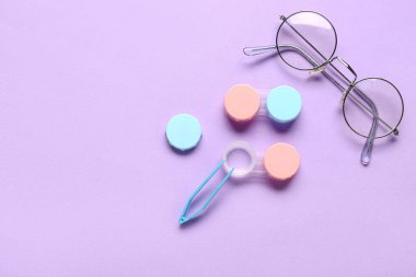 Kontak lensler için gözlük ve leylak arka planda cımbız.