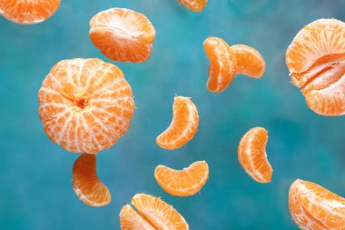 Mavi arka planda soyulmuş tatlı mandalinalar uçuyor