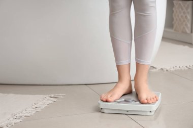 Evde terazinin üzerinde duran genç bir kadın. Kilo verme konsepti