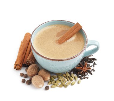 Beyaz arka planda farklı baharat ve ceviz içeren mavi fincanlı lezzetli masala çayı.