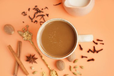 Bej arka planda farklı baharatlı bir fincan lezzetli masala çayı, yakın plan.