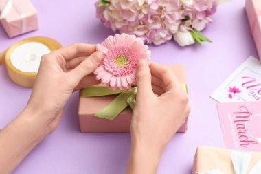 Hediye kutuları ve mor arka planda kartları olan kadın elleri. Uluslararası Kadınlar Günü