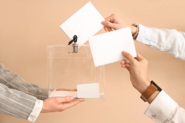 El, oy pusulasını bej arka plandaki oy sandığına koyuyor. Seçim kavramı