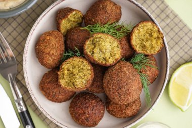 Yeşil arka planda nefis falafel köfteleri, limon ve dereotlu kase, yakın plan.