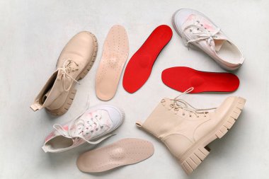 Beyaz arka planda botları ve ortopedik tabanları olan spor ayakkabıları.