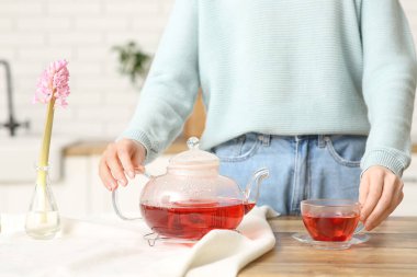 Genç kadın mutfakta kızılcık çayı yapıyor.