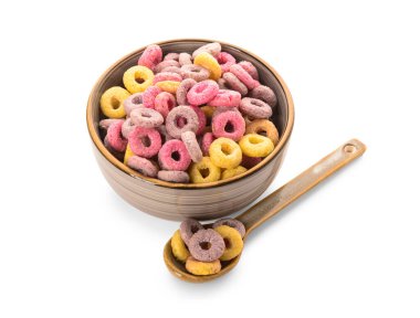 Beyaz arka planda renkli mısır gevreği halkaları olan kase ve kaşık.