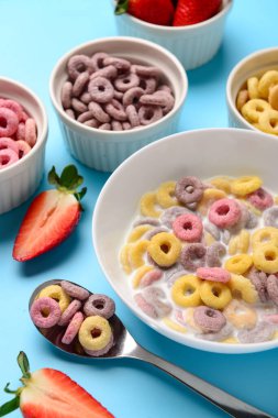 Sütlü ve mavi arka planda çilekli renkli mısır gevreği halkaları.