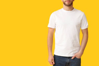 Sarı arka planda şık tişörtlü bir adam.