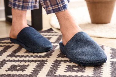 Evde mavi terlik giyen adamın bacakları. Yakın çekim.