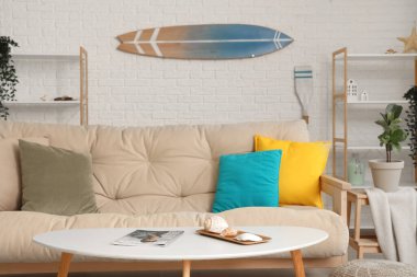 Beyaz kanepe ve sörf tahtasıyla aydınlık oturma odasının içinde.