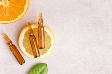 C vitamini ve hafif arkaplanda taze narenciye içeren ampuller.