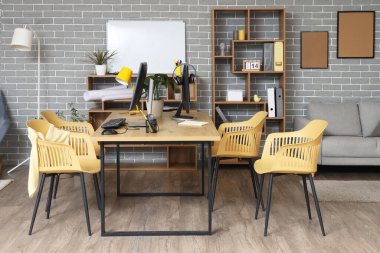 Çalışma yeri, raf üniteleri ve bitkileri olan şık bir ofis.