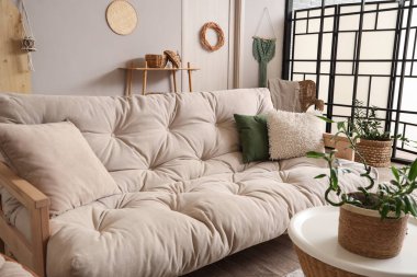 Kahve masası, yastıklar ve beyaz kanepe üzerinde bambu sapları olan hafif oturma odasının şık bir iç mekanı.