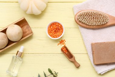 Deniz tuzu, ahşap masaj topları, sabun çubuğu, havlu ve masaj vücut fırçası ile güzel kompozisyon sarı ahşap arka planda, yakın plan