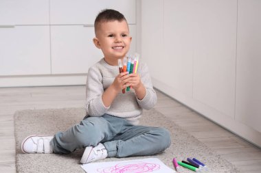 Mutfakta yere keçeli kalem çizen sevimli bir çocuk.