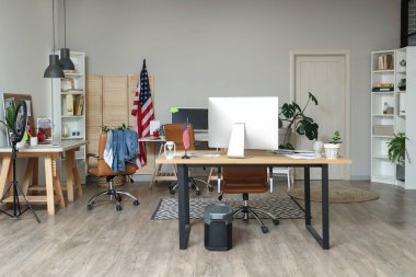 Çalışma alanları, modern bilgisayarlar, koltuklar ve ABD bayrakları olan geniş ofisin şık iç tasarımı