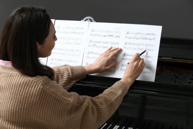 Piyanoda nota okuyan genç bir kadın.