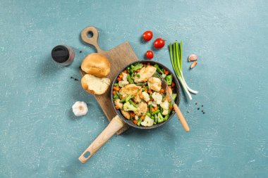 Renkli arkaplanda kızarmış tavuk fileto, sebze ve çörek kompozisyonu