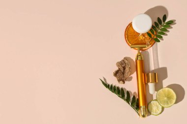 Yüz masajı silindiri, krem, temel yağ ve hafif arka planda bitkiler