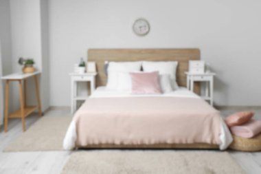 Beyaz duvarında yatak, yastık ve saat olan şık bir yatak odası.