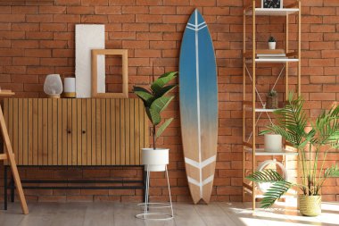 Çekmeceler, sörf tahtası ve raflar oturma odasındaki tuğla duvarın yanında.