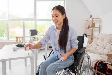 Tekerlekli sandalyedeki genç Asyalı kadın evinde raf montajı yapıyor.