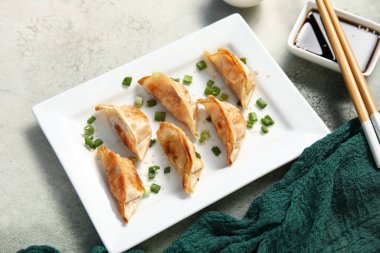Kızarmış Japon gyoza tabağı ve arka planda soya sosu.
