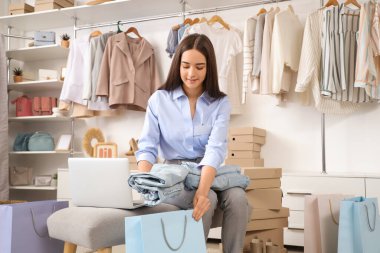 Kadın satıcı giysi mağazasında online kot pantolon siparişi vermiş.