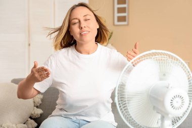 Evinde elektrikli yelpazesi olan güzel, olgun, mutlu bir kadın.