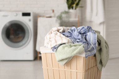 Çamaşır makinesinin yanında çamaşır sepeti var.