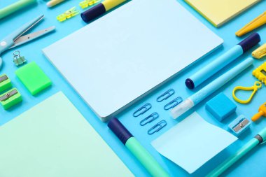 Mavi arkaplanda farklı kırtasiye malzemesi olan kompozisyon, yakın plan