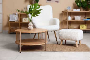 Masada ve şık koltukta tropikal canavar yaprakları olan modern bir oturma odası.