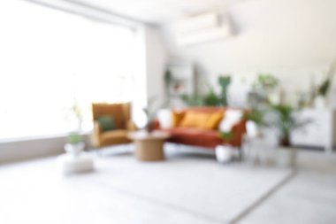 Yeşil çiçekleri, kanepesi ve koltuğu olan bulanık oturma odası.