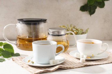 Çaydanlıklı ve beyaz arka planda yapraklı lezzetli ıhlamur çayları.