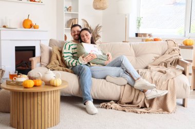 Mutlu genç çift, sonbahar günü evde otururken çerçevelerini boyayıp resim yapıyorlar.