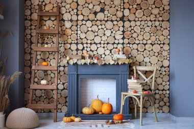 Şömineli, koltuklu ve balkabaklı bir oturma odası. Sonbahar konsepti