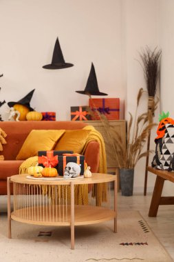 Kahverengi kanepesi, sehpası, Cadılar Bayramı süslemeleri ve hediye kutuları olan festival salonunun içi.