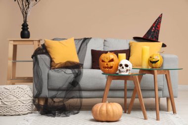 Oturma odasının içinde kanepe, masa ve Cadılar Bayramı balkabakları var.