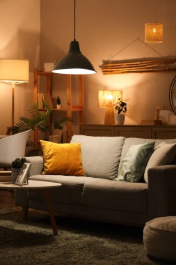 İçinde kanepe, sehpa ve parlayan lambalar olan karanlık bir oturma odası.