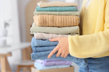 Genç bir kadın temiz giysileri evde tutuyor, yakın plan.