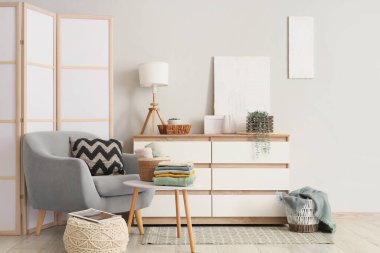 Gri koltuğu, şifoniyeri ve sehpası olan aydınlık oturma odasının içinde.