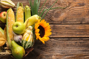 Tahta arka planda farklı taze sebzeler ve meyvelerle dolu bir sepet. Hasat festivali
