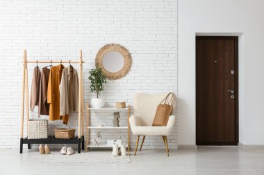 Koridorun içinde koltuk, ayna ve şık kıyafetler var.