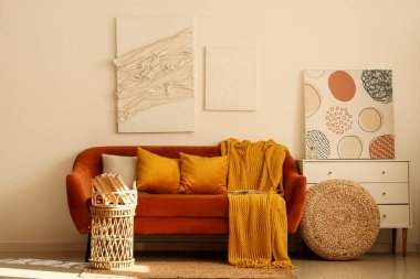 Rahat bir kanepe, çekmeceler ve oturma odasının içinde kitaplar olan tepsiler.