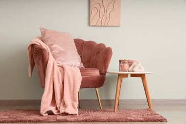 Kahve masası ve yeşil duvarın yanındaki koltukta sıcak battaniye.