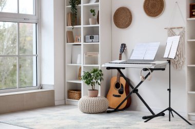 Oturma odasının içinde sentezleyici, müzik standı ve raf üniteleri var.